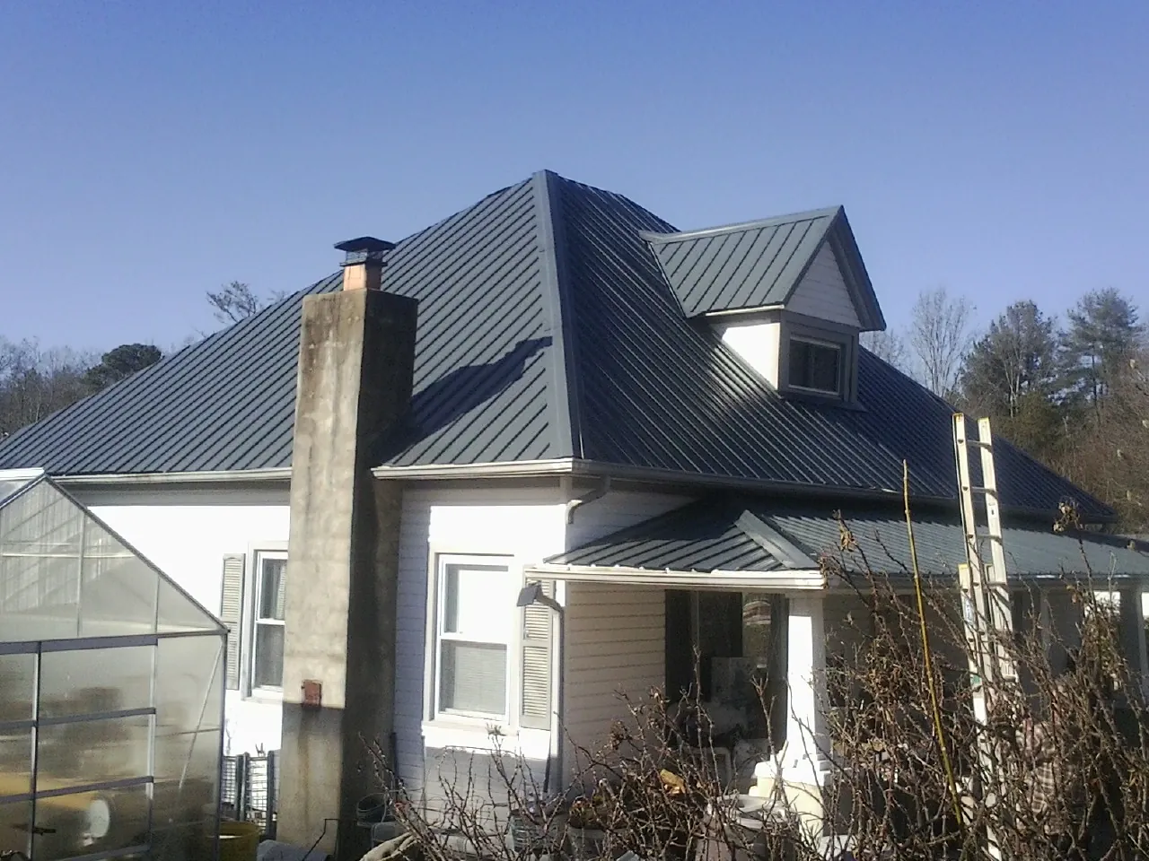 Dark blue standing seam metal roof on a white farmhouse with dormer — Slate & Tile Roof Repair by Roofing Brothers in North Andover