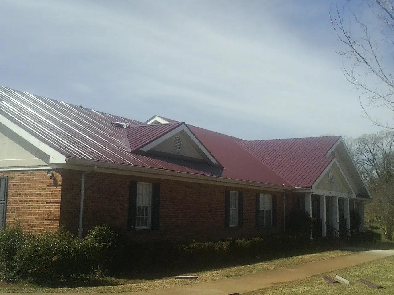 Red metal roof with gabled entries on a long brick building in North Andover