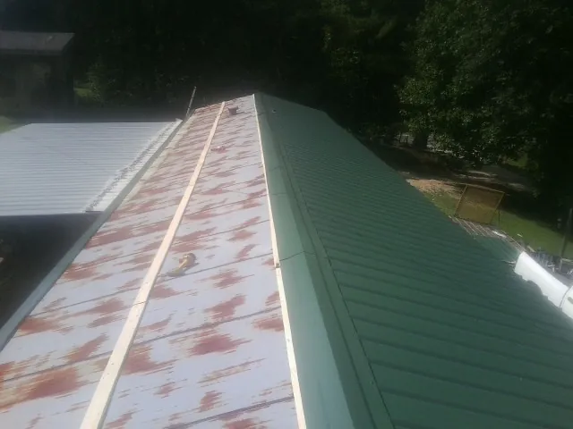 Old rusted panels beside newly installed green metal roofing — Wind Damage Roof Repair by Roofing Brothers in North Andover