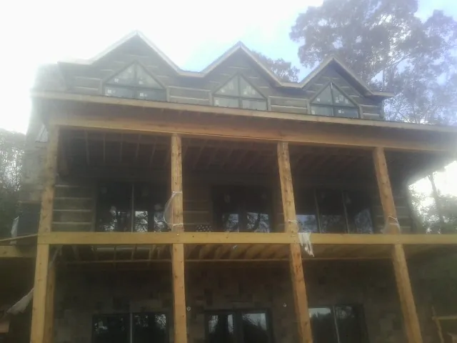 Dormers and porch framing on a large log home under construction — Roof Coating work by our crew in North Andover