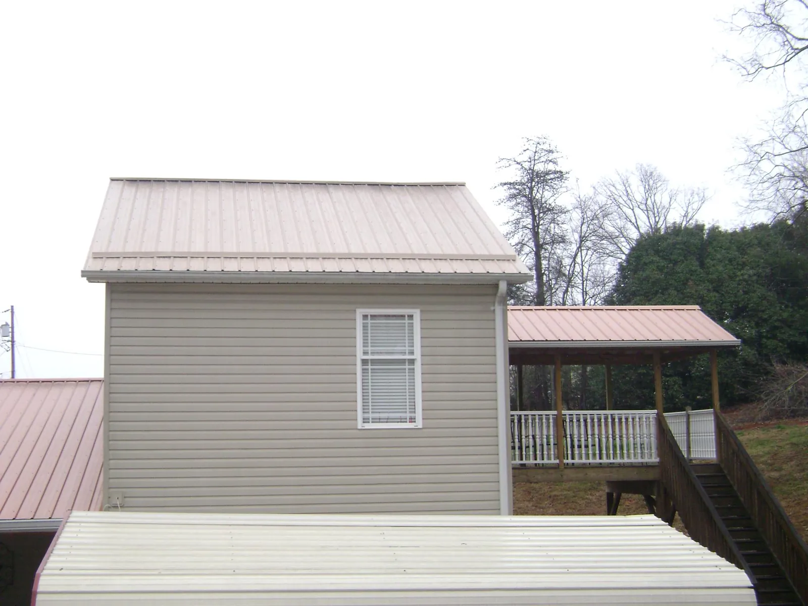 Tan metal roofs on a two story addition and attached porch, from a Roof Replacement job in North Andover