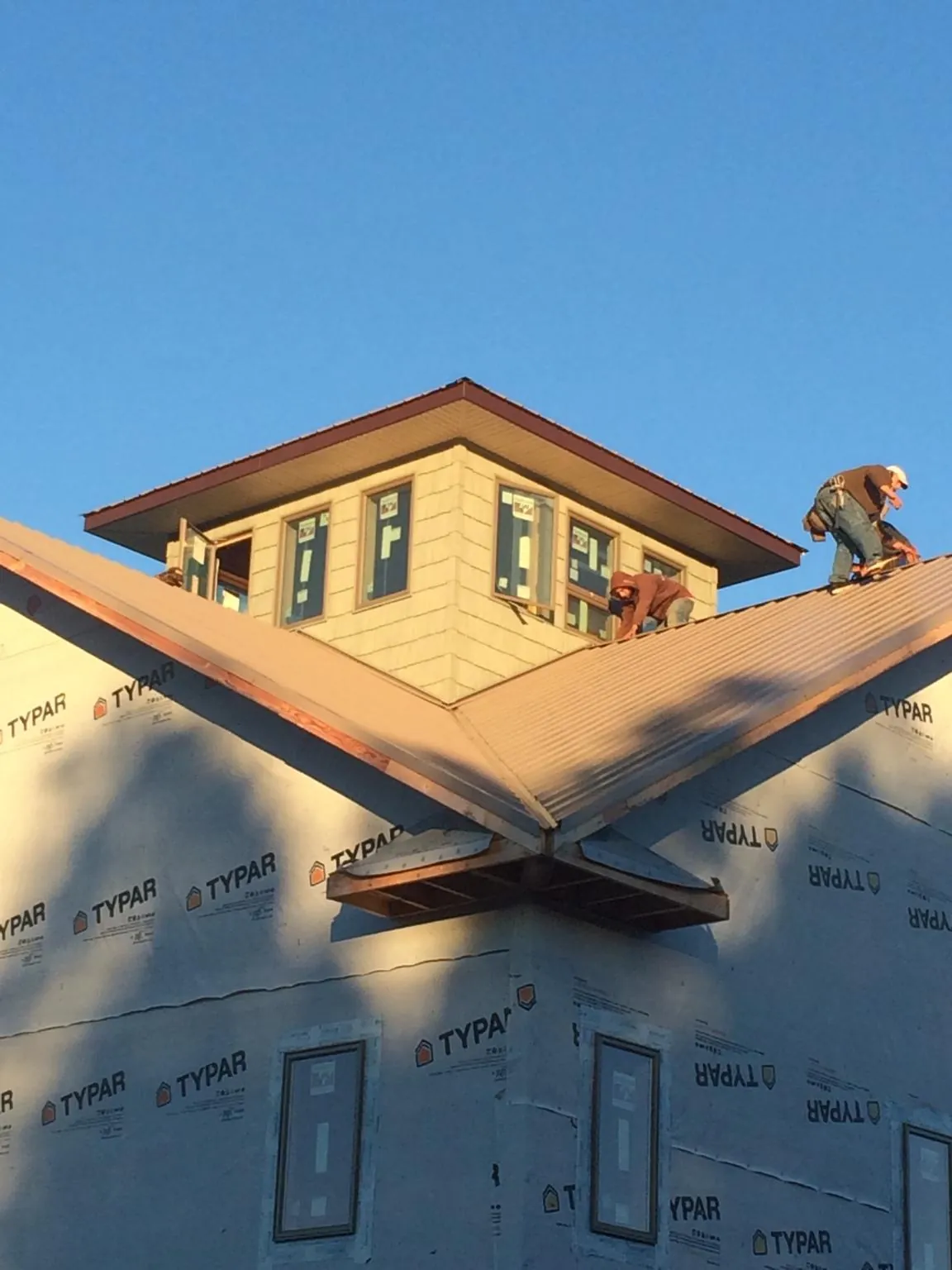 Roofers working around a rooftop cupola on a new metal roof at sunset — Roof Waterproofing in North Andover by Roofing Brothers